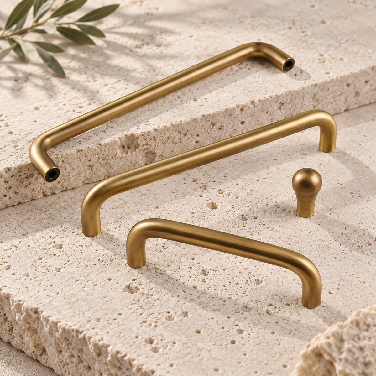 Antique brass rounded cabinet pulls and slim knob arranged on limestone