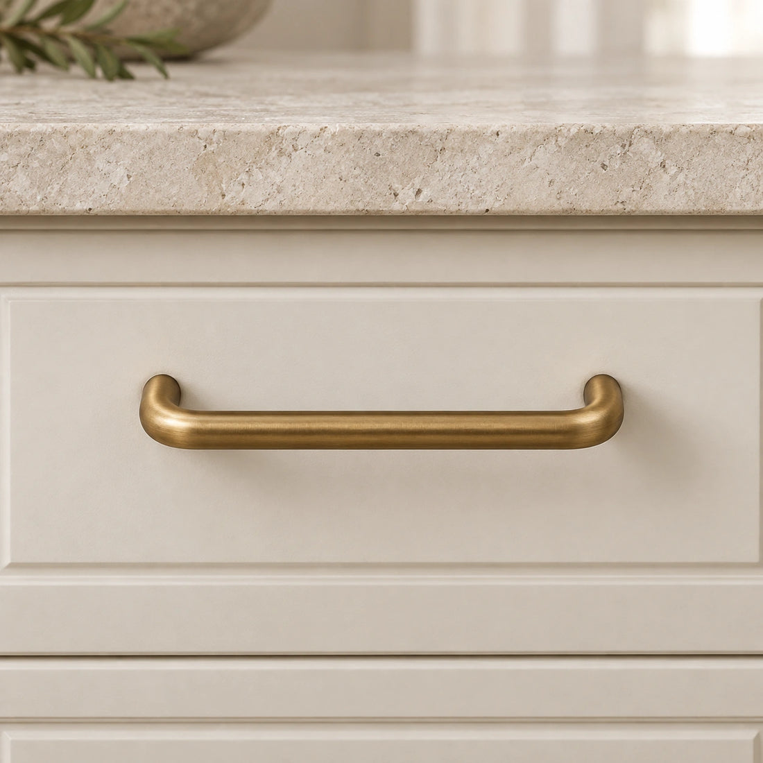 Antique brass rounded cabinet pulls and slim knob arranged on limestone