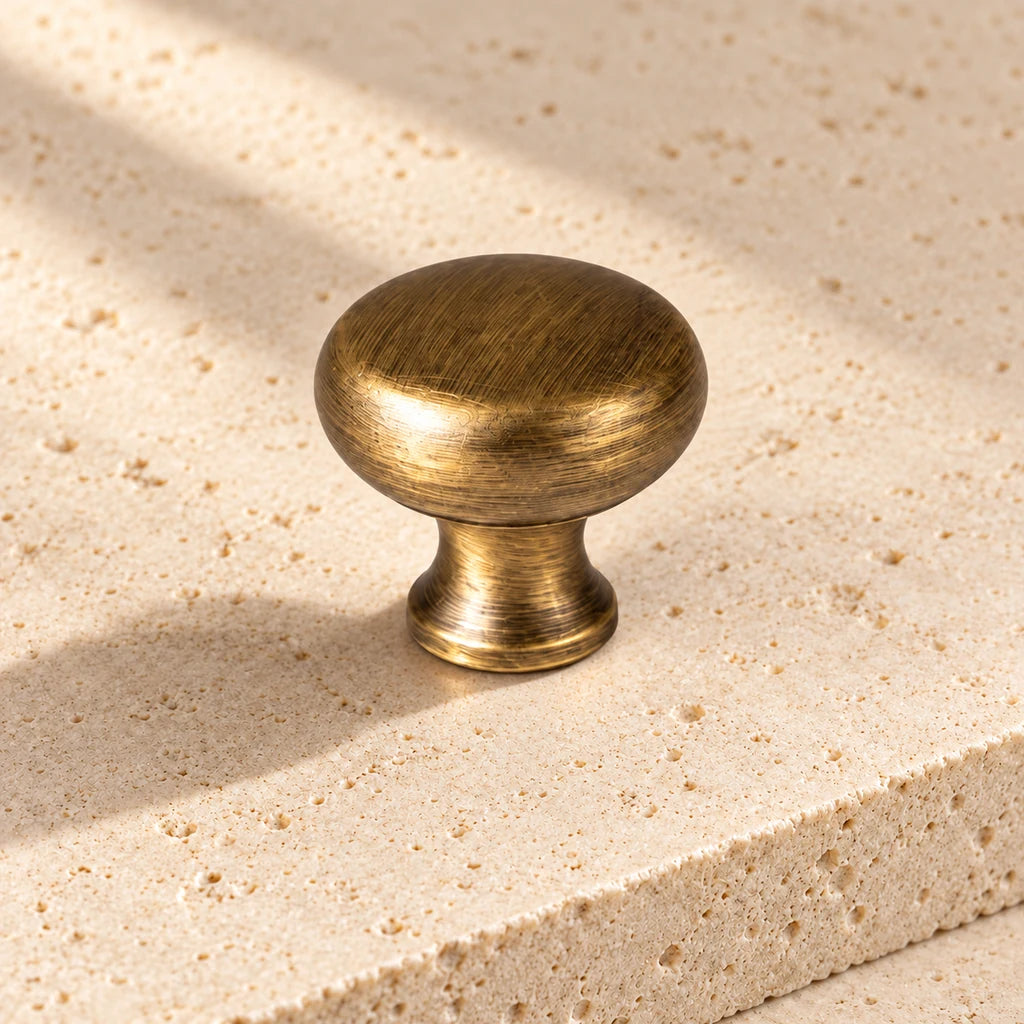 antique brass rounded mushroom knob on pale limestone.