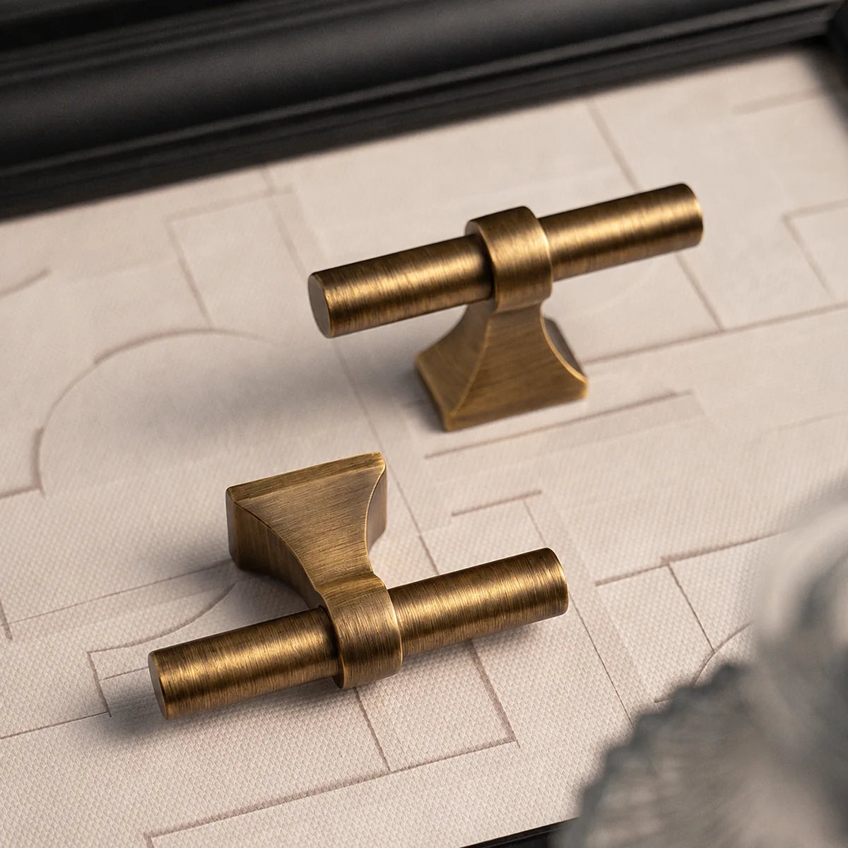 Close-up of solid brass saddle-base T-knobs showing brushed finish and sculpted mounting bases