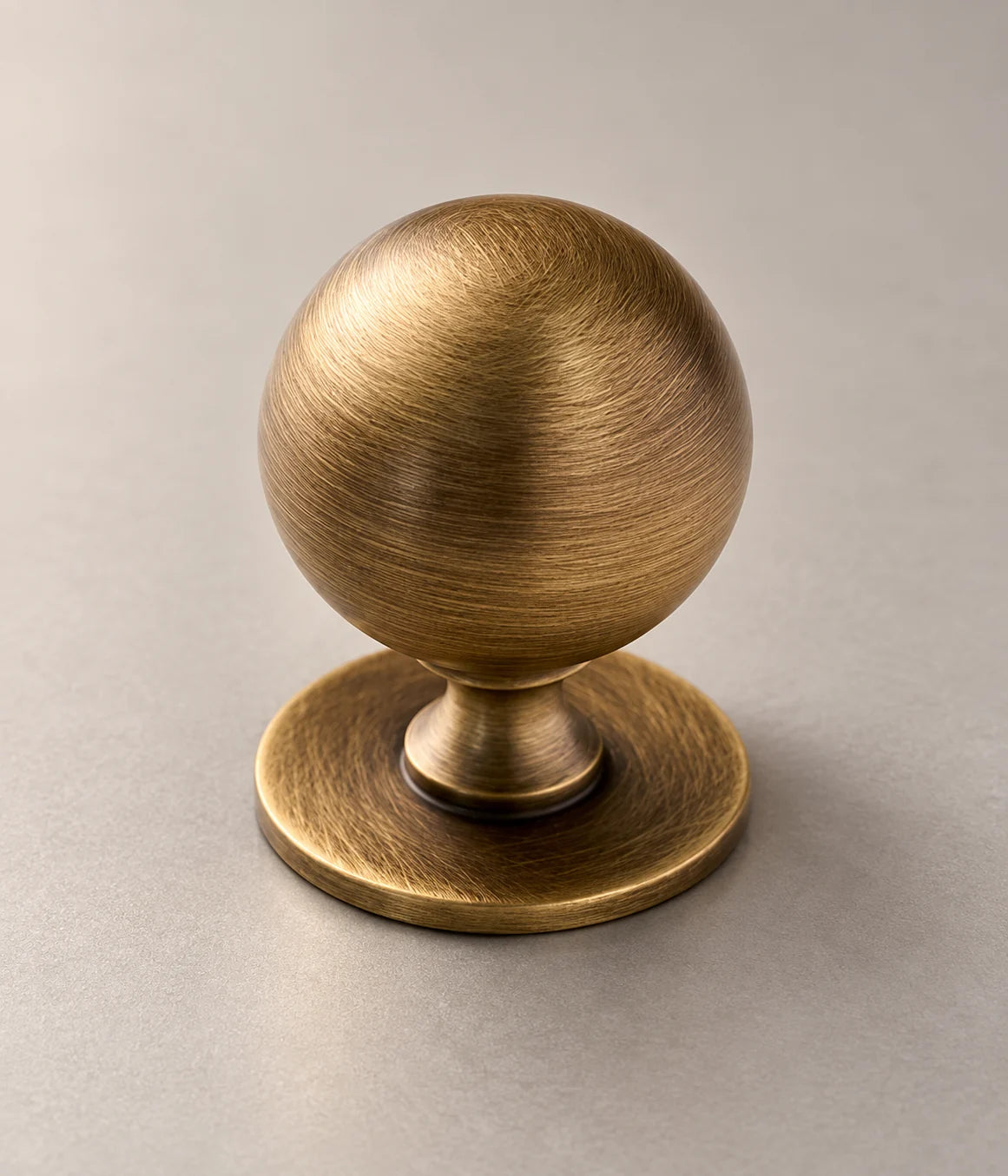 Close view of the brushed brass ball grip and flared neck of the cabinet knob