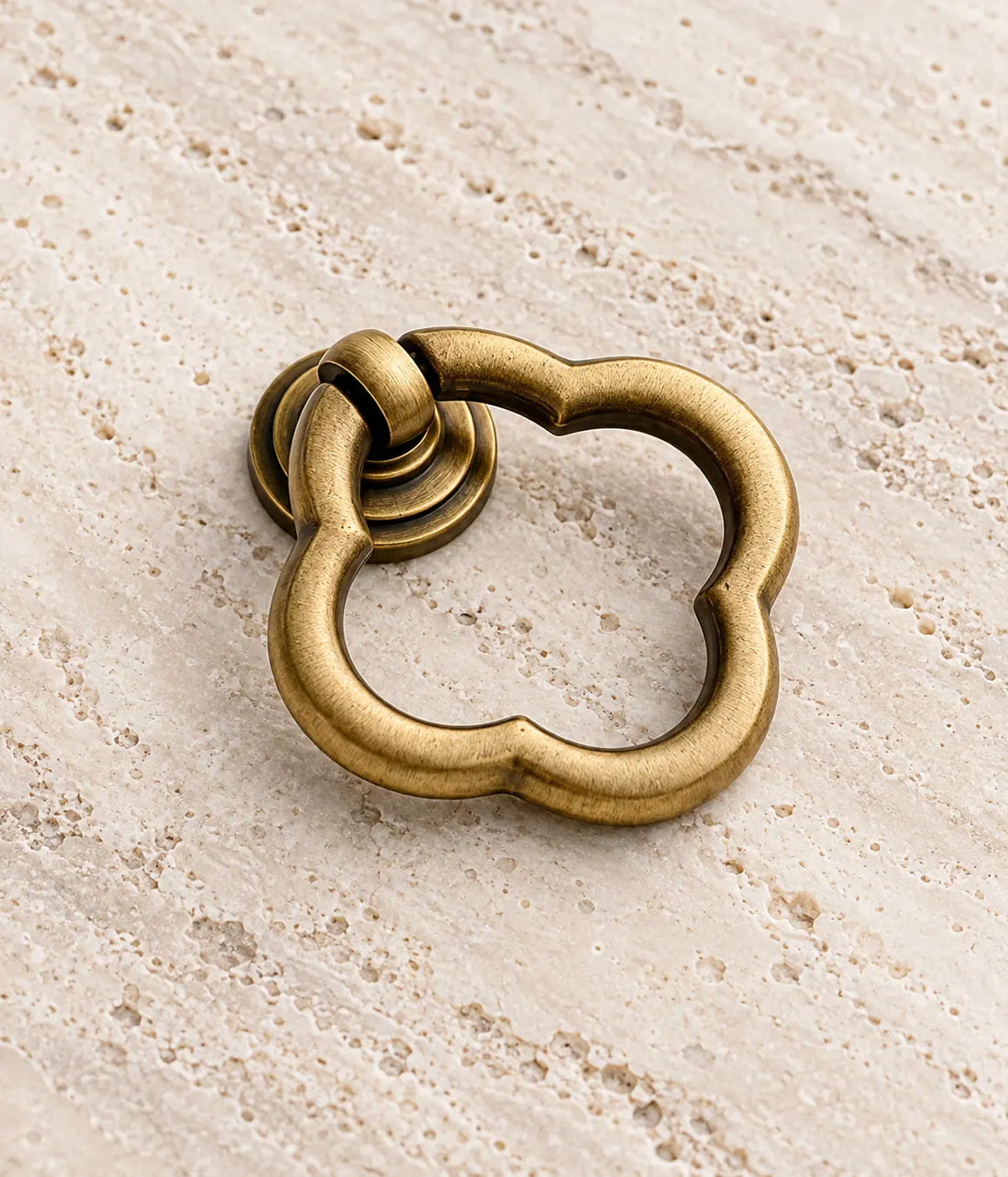 Antique brass scalloped ring pulls arranged on warm limestone