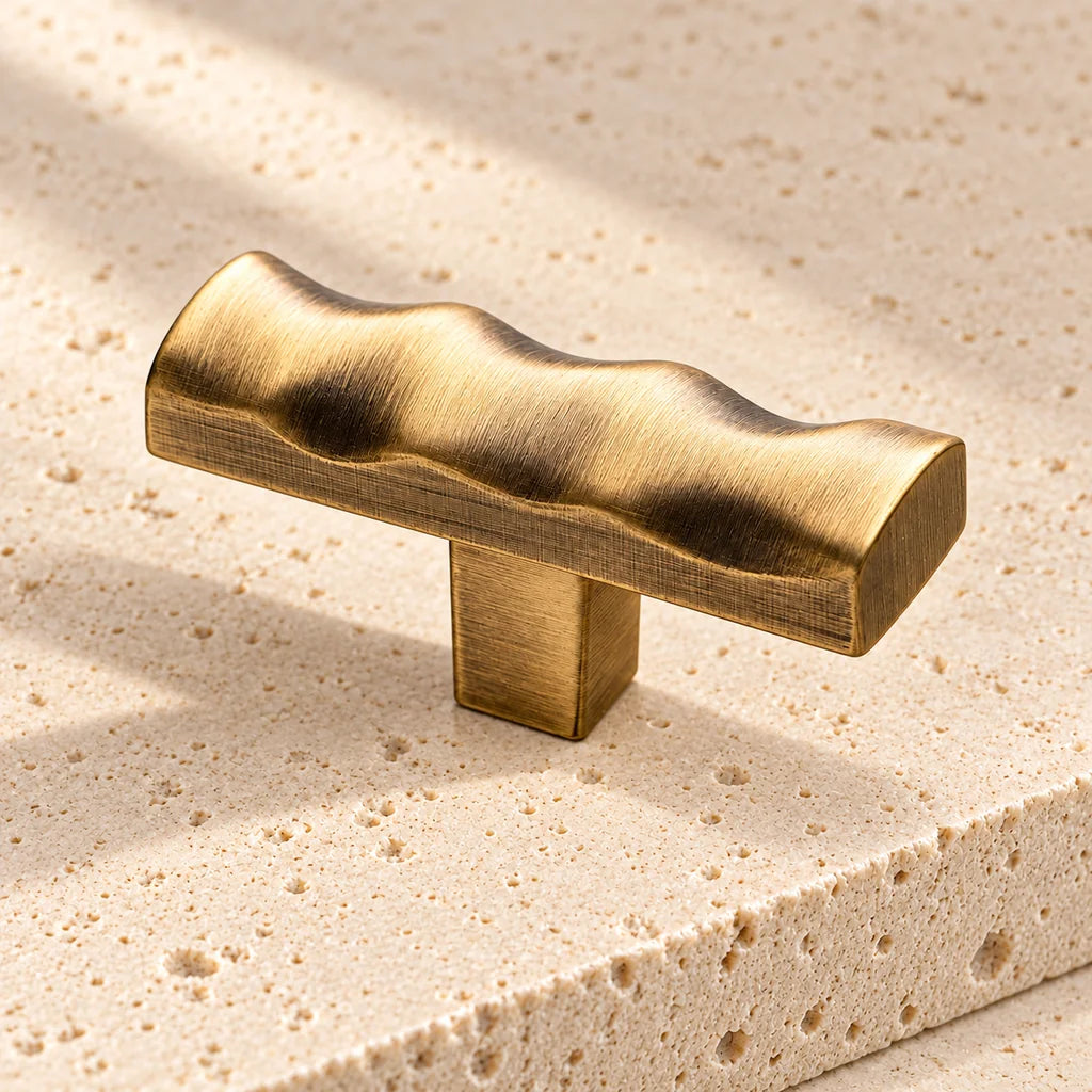 antique brass scalloped t knob on pale limestone.