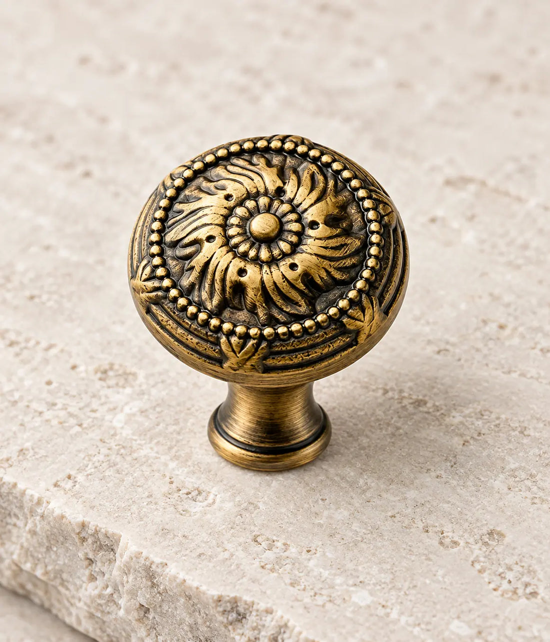 Antique brass scrollwork cabinet knobs arranged on pale limestone