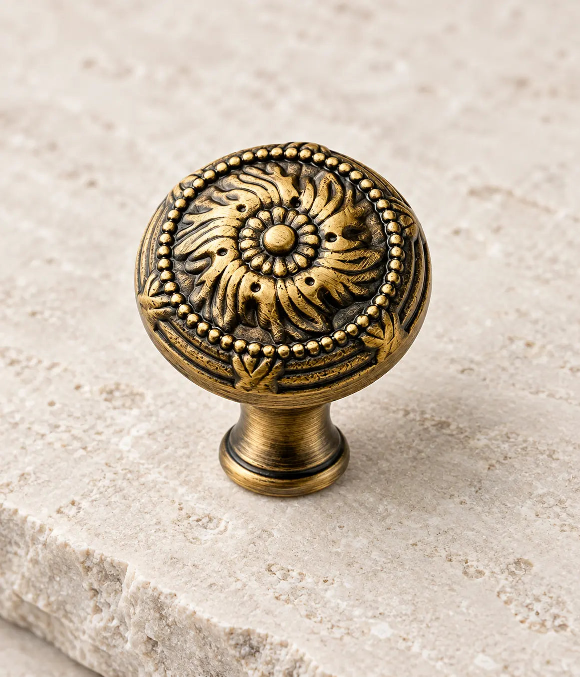 Close-up of raised scrollwork and bead borders on an antique brass cabinet knob