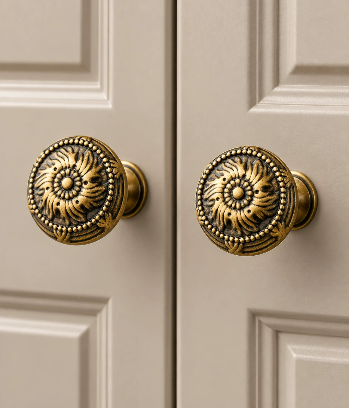 Antique brass scrollwork knobs installed on warm neutral cabinet doors