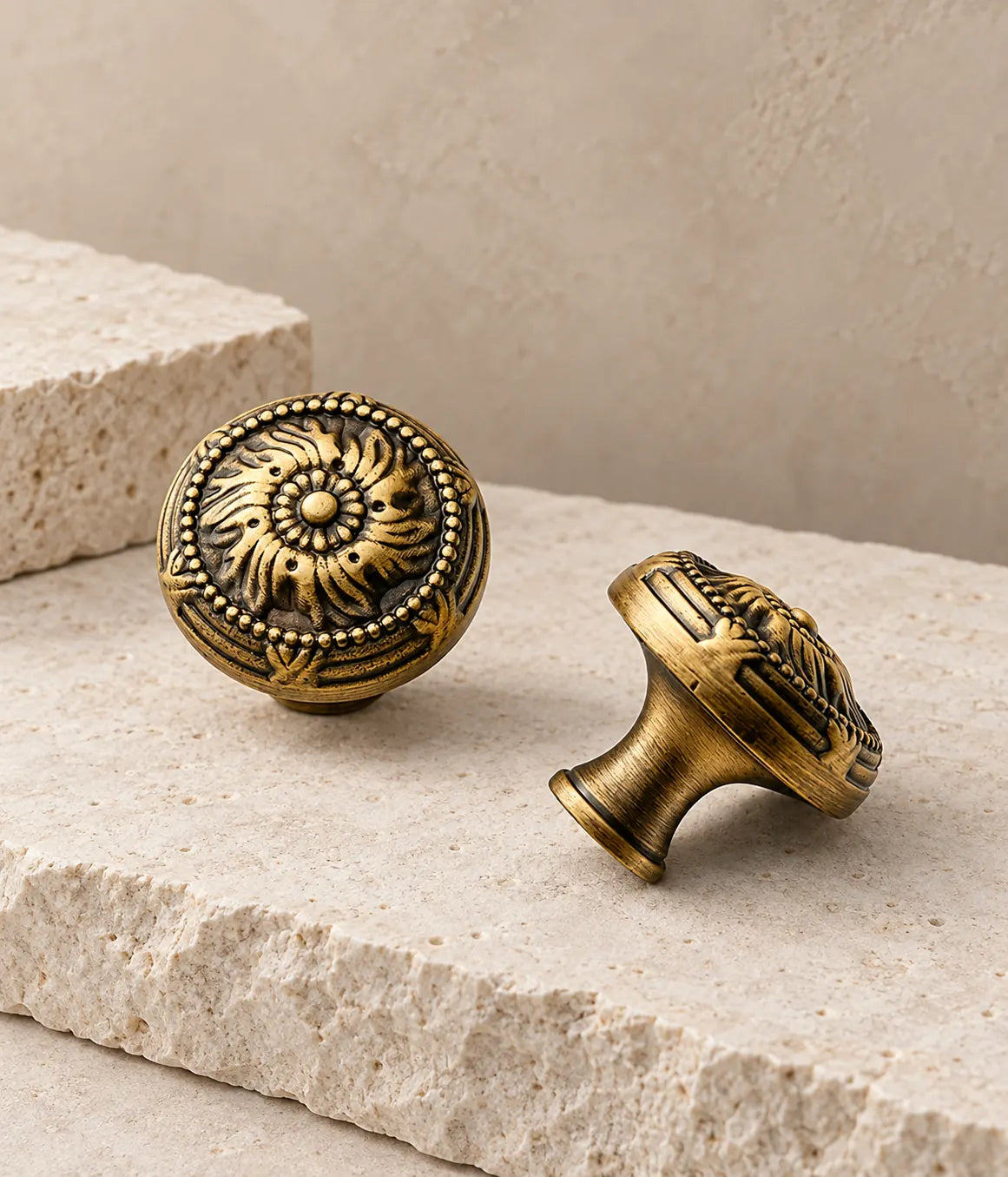 Antique brass scrollwork cabinet knobs arranged on pale limestone