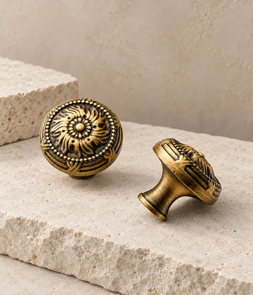 Antique brass scrollwork cabinet knobs arranged on pale limestone
