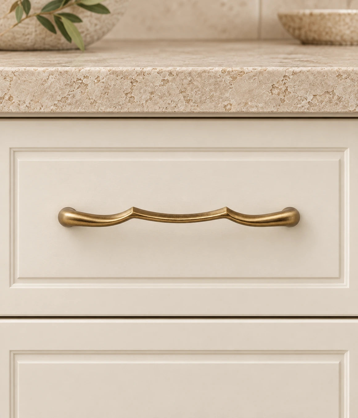 Antique Brass Sculpted Arch Cabinet Pulls mounted on an ivory cabinet drawer