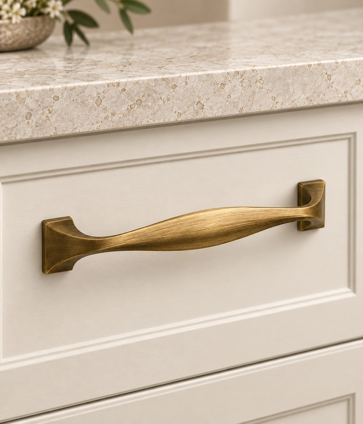 Antique Brass Sculpted Bow Cabinet Pulls installed on an ivory cabinet drawer