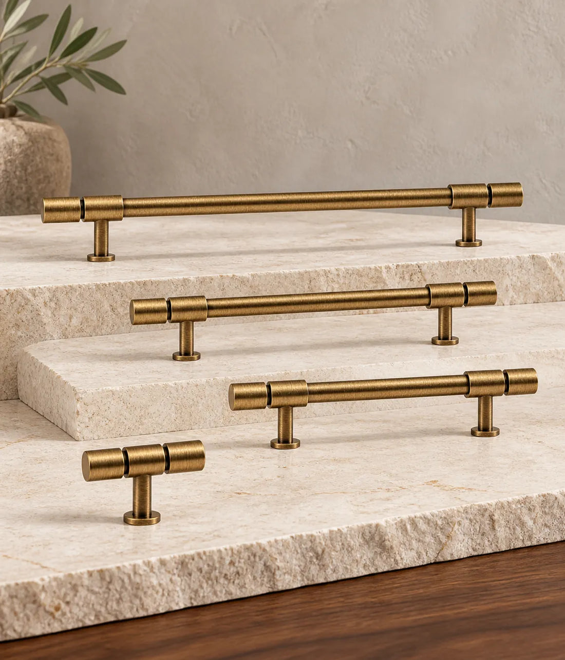 Antique brass segmented-end cabinet pulls and T-knob arranged on pale limestone and walnut