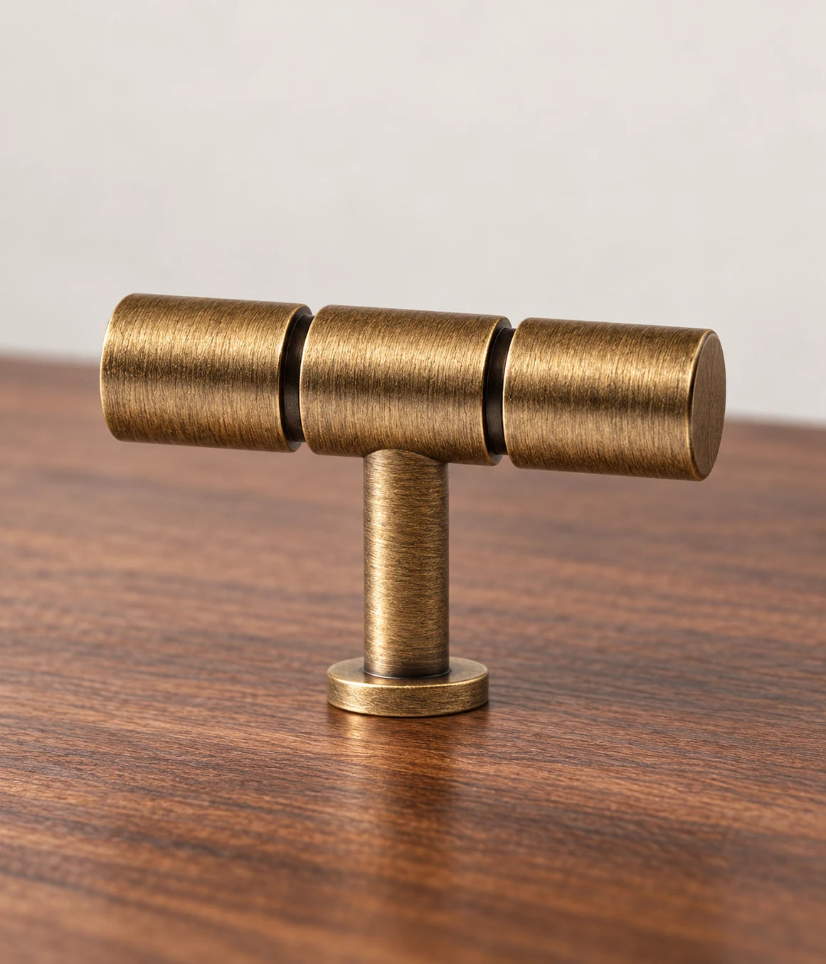 Three-section antique brass T-knob with recessed seams and a round mounting foot