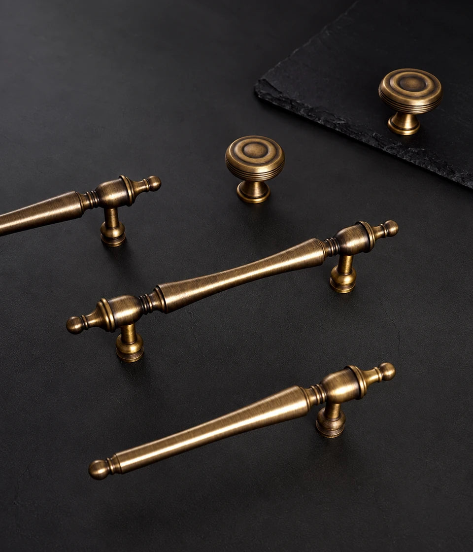 Antique brass slender finial pulls and grooved round knobs on dark stone