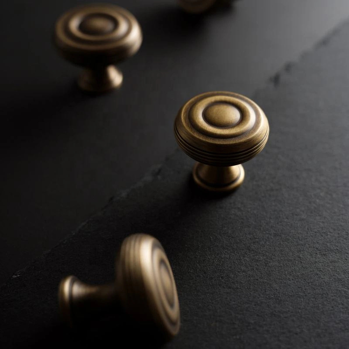 Concentric face and grooved rim detail on antique brass cabinet knobs