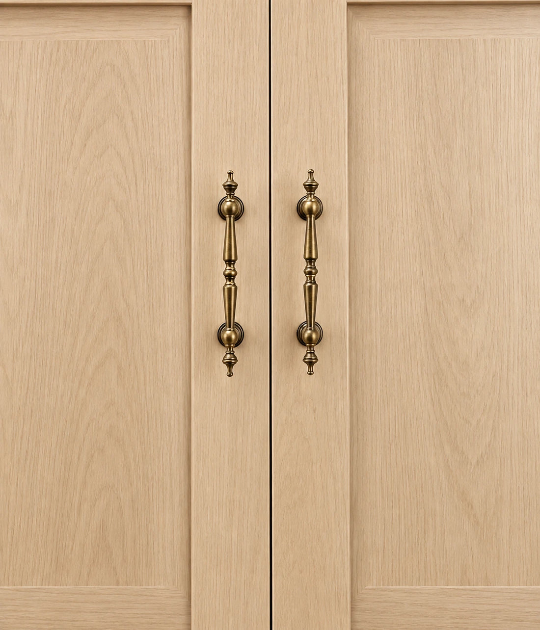 Antique brass spindle cabinet pulls and ball knob arranged on warm limestone