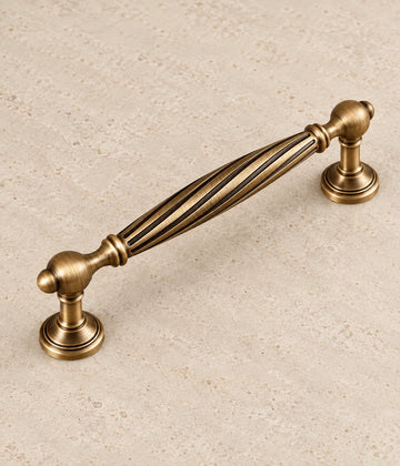 Antique Brass Spiral Cabinet Pulls & Fluted Knobs on warm ivory limestone