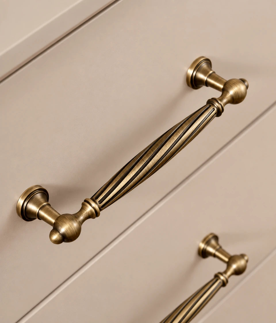 Antique brass spiral cabinet pull installed on cream drawer