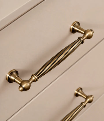 Antique brass spiral cabinet pull installed on cream drawer