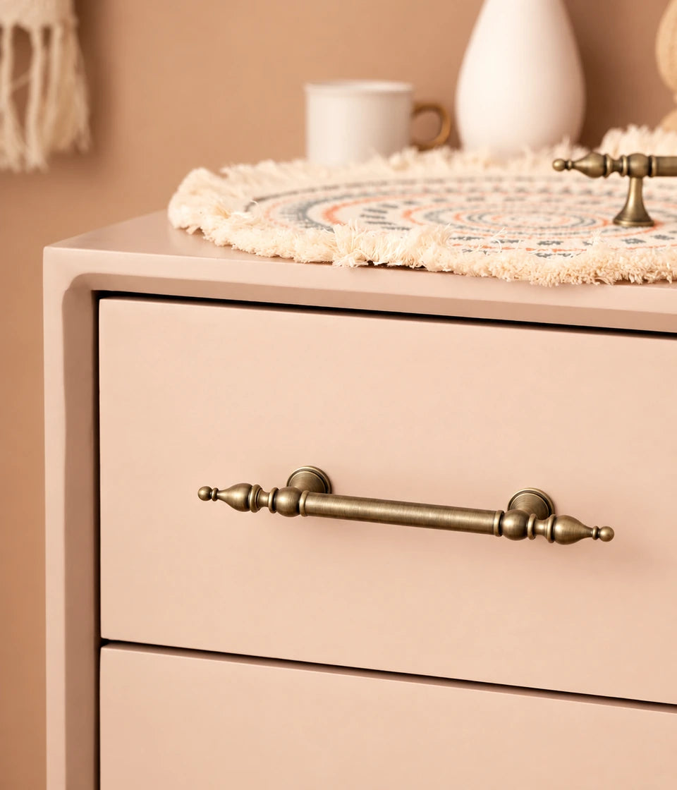 Spire-finial brass drawer pull on a peach cabinet drawer