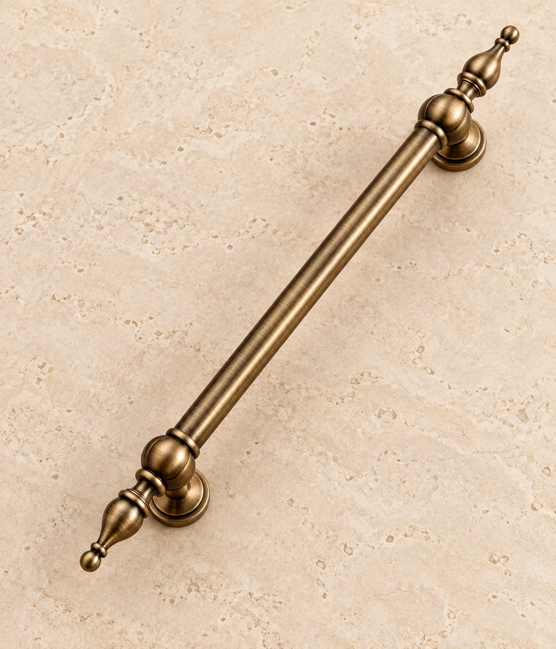 Antique Brass Spire-Finial Cabinet Pulls on warm ivory limestone