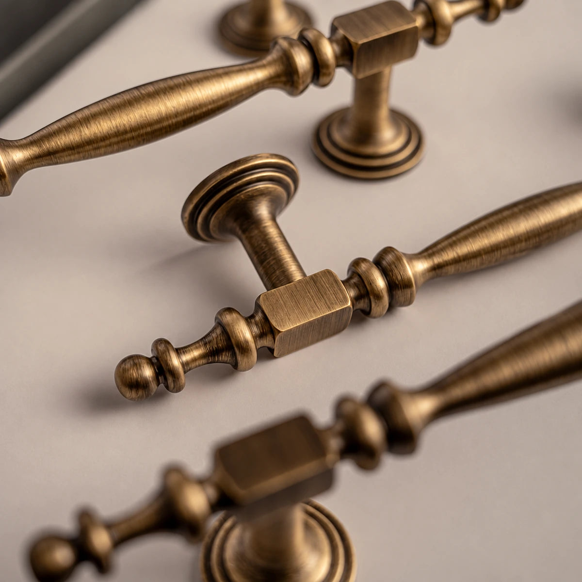 Close-up of a brass cabinet pull with square collar, spindle grip and ball-tipped finial