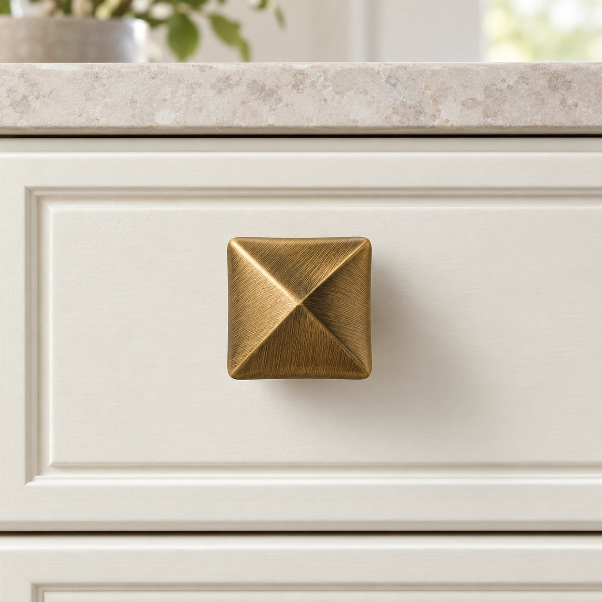 Square pyramid brass knob correctly installed on an ivory cabinet drawer