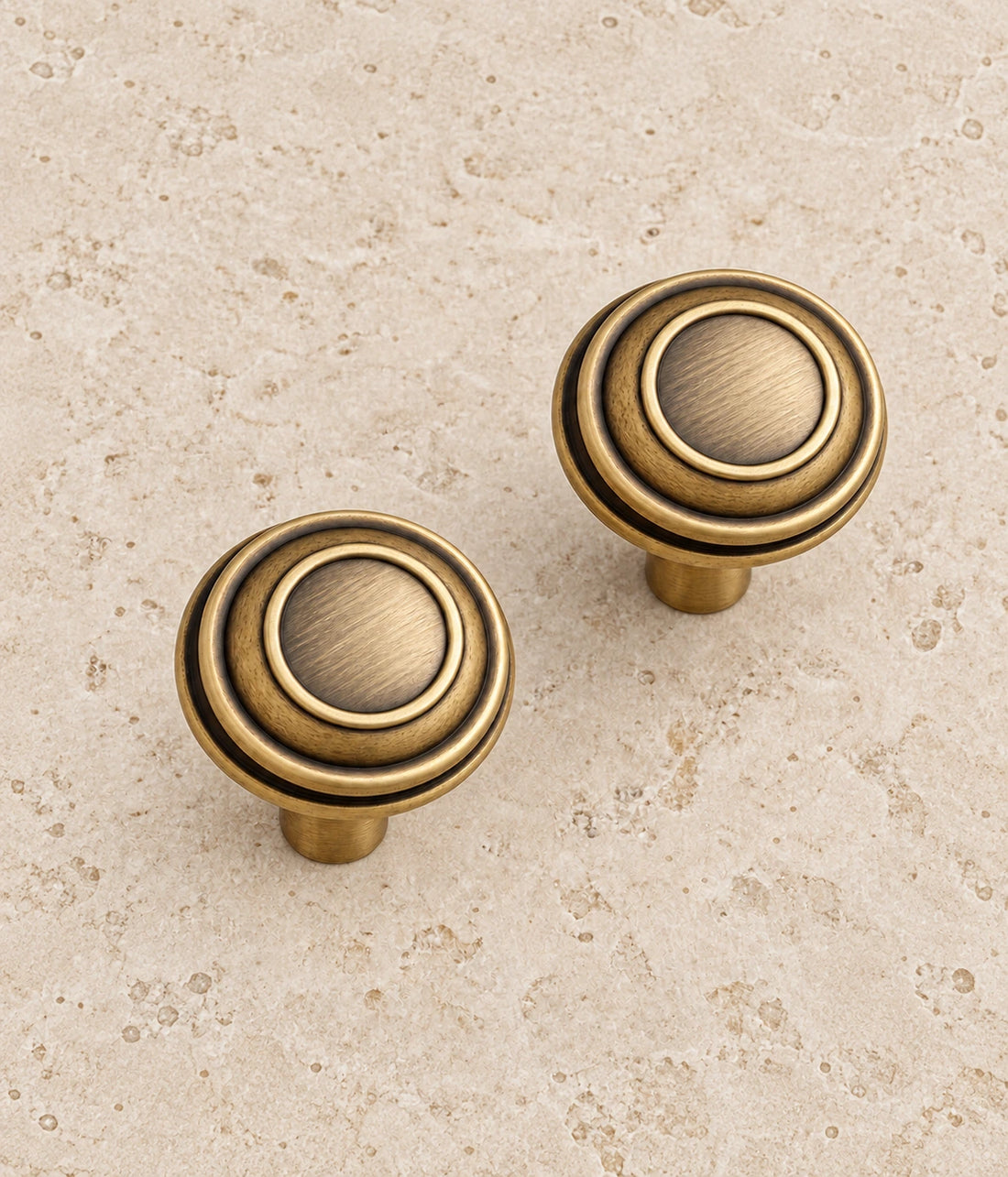 Antique Brass Stepped Round Cabinet Knob on warm limestone