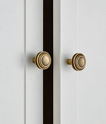 Antique brass stepped round knobs installed on white cabinet doors