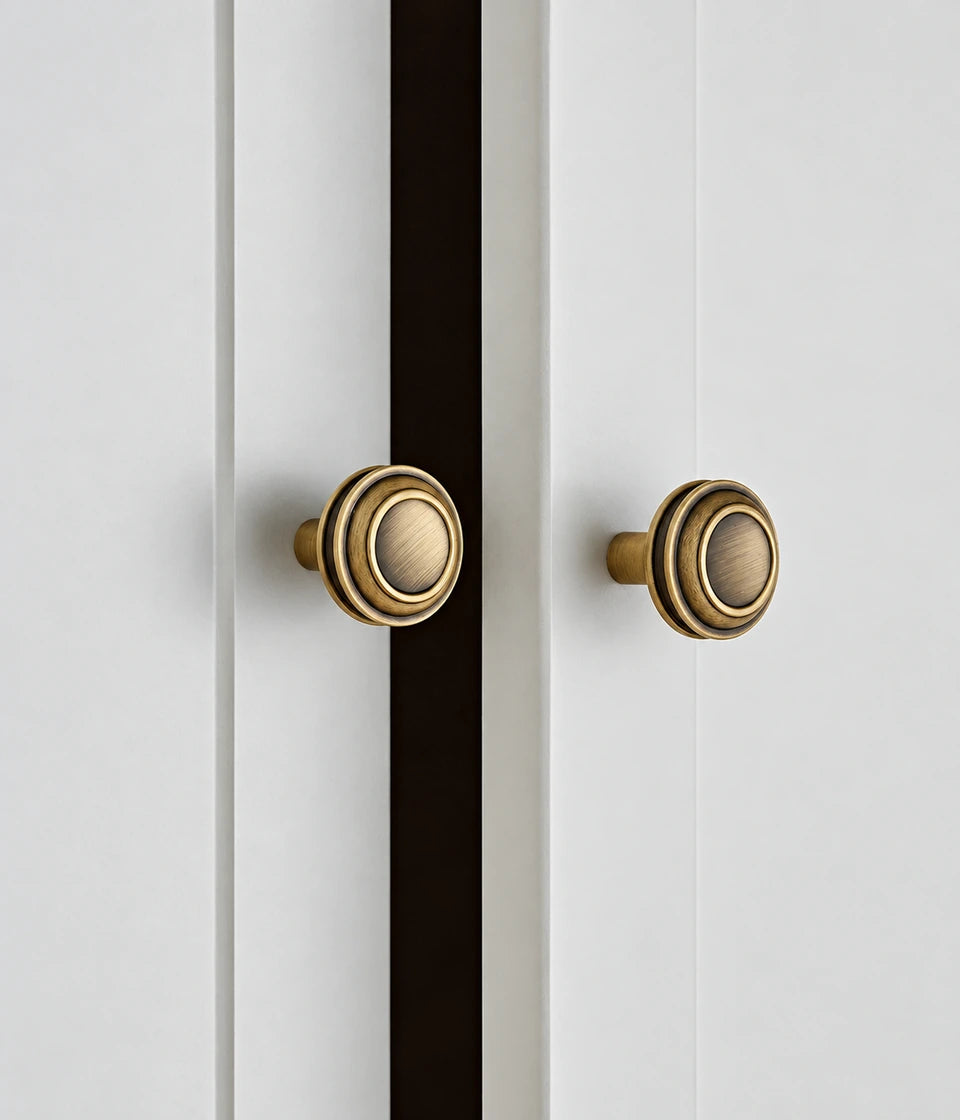 Antique brass stepped round knobs installed on white cabinet doors