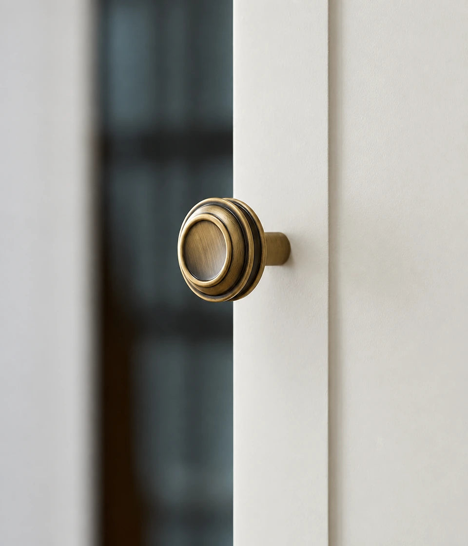 Side view of an antique brass stepped round cabinet knob