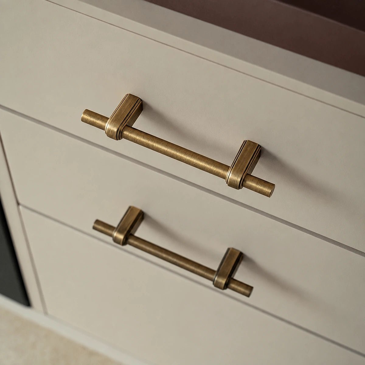 Antique brass strap-post pulls fitted horizontally on cream drawers