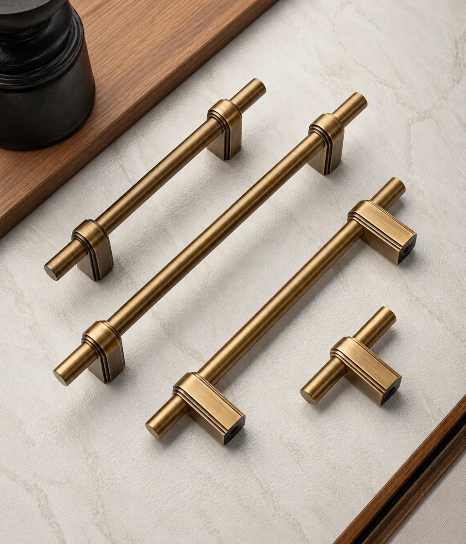 Antique brass strap-post cabinet pulls and matching T-knob arranged together