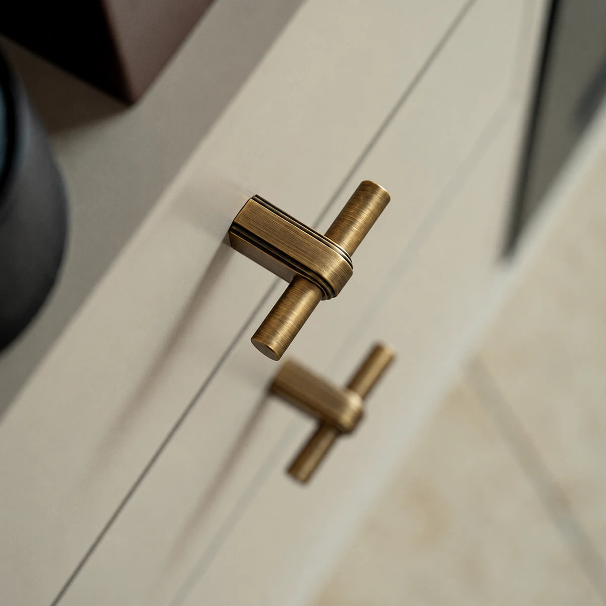 Antique brass strap T-knob with grooved mounting post on a cabinet