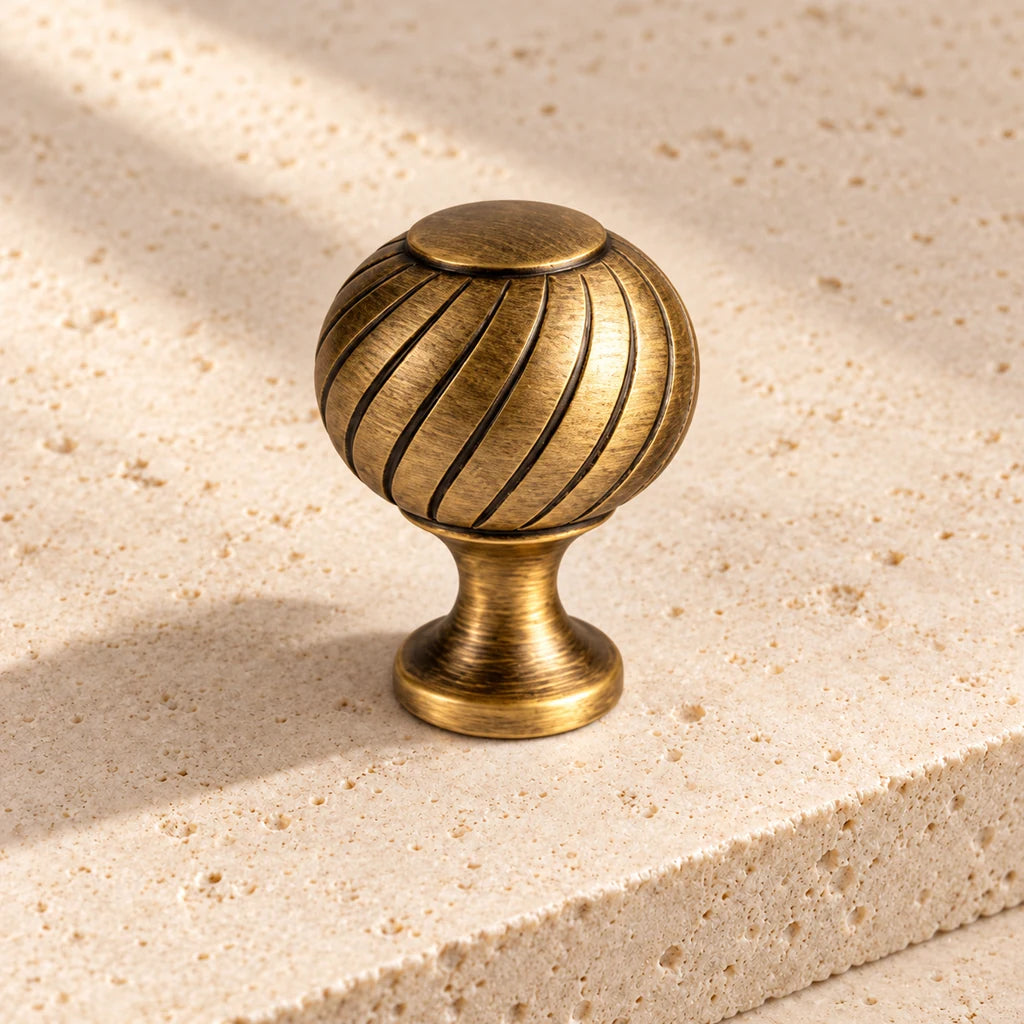 antique brass swirl finial knob limestone on pale limestone.