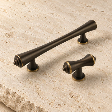 Antique brass tapered finial cabinet pull and T-knob arranged on limestone