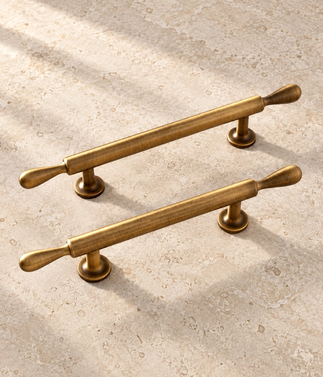 Antique Brass Teardrop-Finial Cabinet Pulls on warm ivory limestone