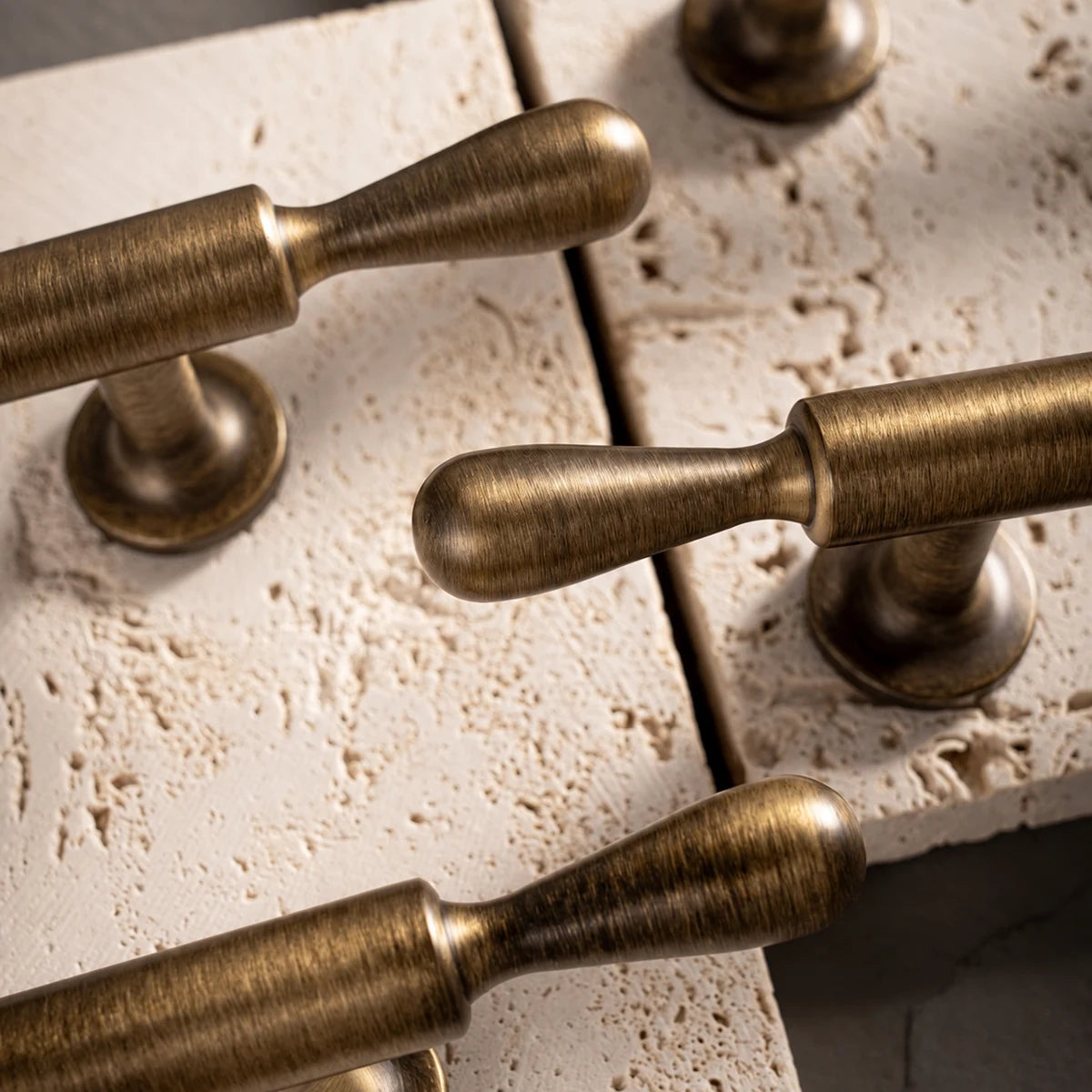 Close-up of antique brass teardrop finials and brushed cylinder grips