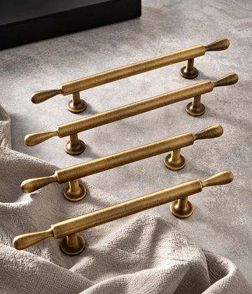 Antique brass teardrop-finial cabinet pulls on stone and linen