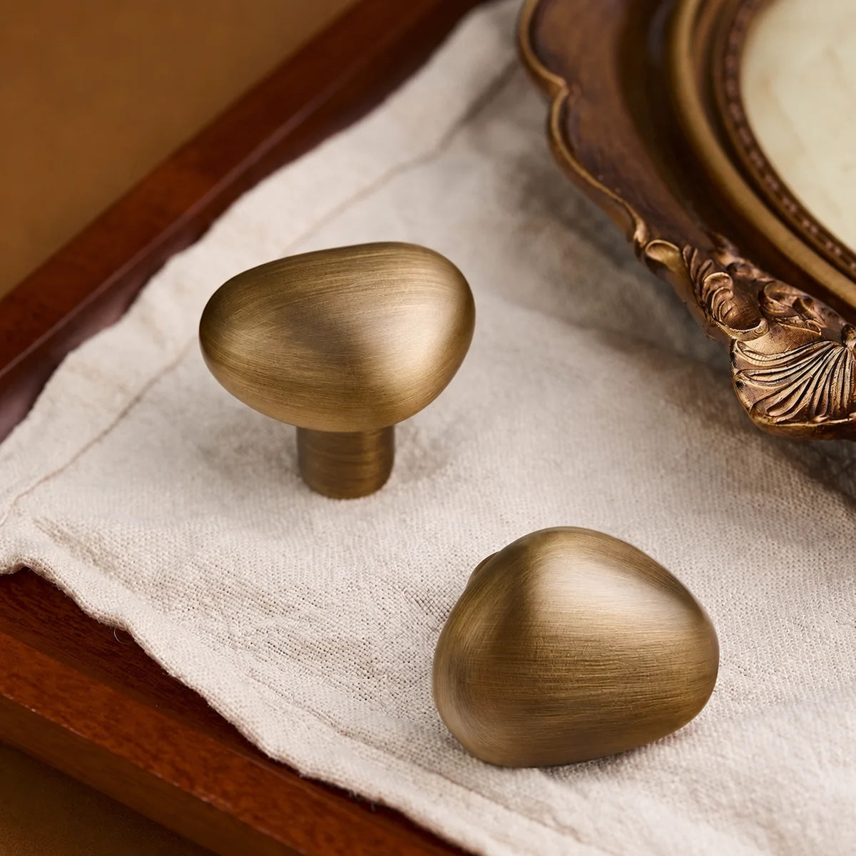 Rounded teardrop knob faces with antique brushed brass texture
