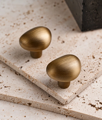 Antique brass teardrop cabinet knobs on pale stone
