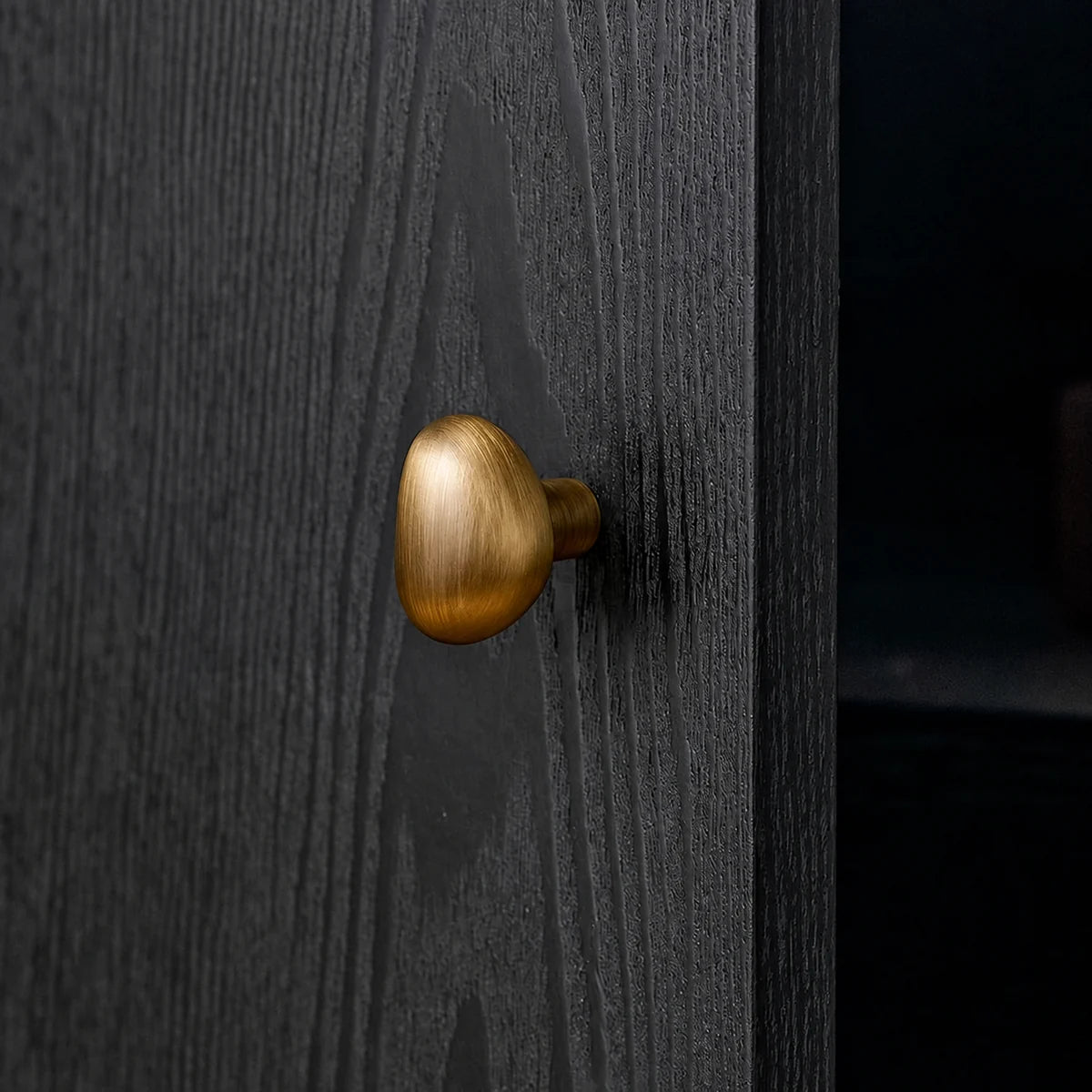 Antique brass teardrop cabinet knob installed on dark wood
