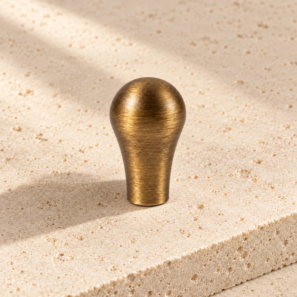 antique brass teardrop knob on pale limestone.