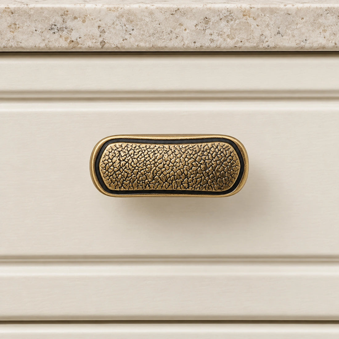 Antique brass textured oblong T-knob with smooth border on pale limestone