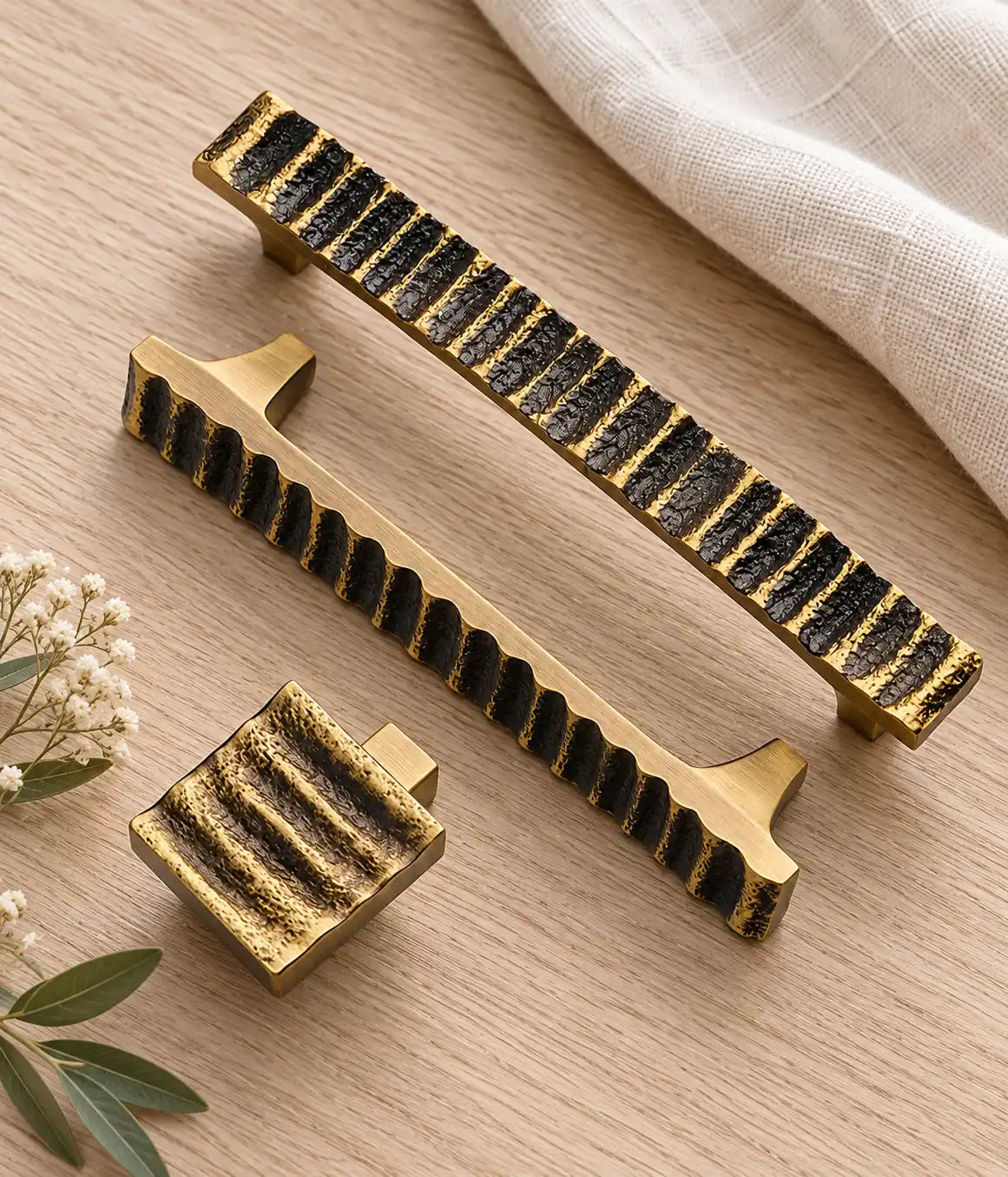 Wave-textured antique brass handles styled on pale oak and ivory linen
