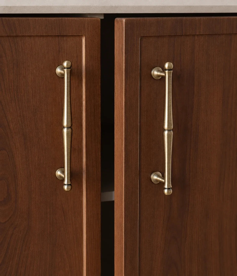 Turned antique brass cabinet pulls installed on walnut doors