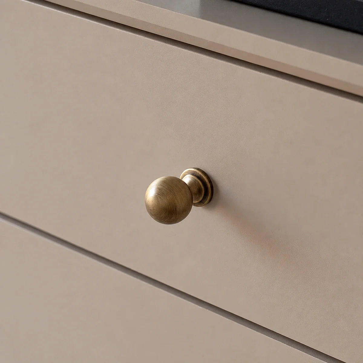 Antique brushed brass ball knob installed on a drawer