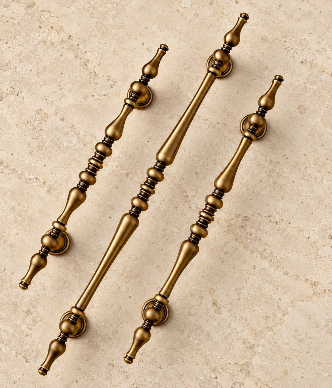 Antique Brass Turned Spindle Cabinet Pulls on warm limestone