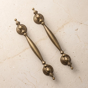 Antique brass urn-end cabinet pulls in two sizes on premium limestone