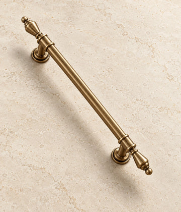 Antique Brass Urn-Finial Cabinet Pulls on warm ivory limestone