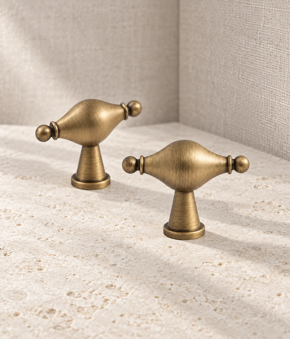 Antique brass urn-shaped spindle T-knobs arranged on pale limestone